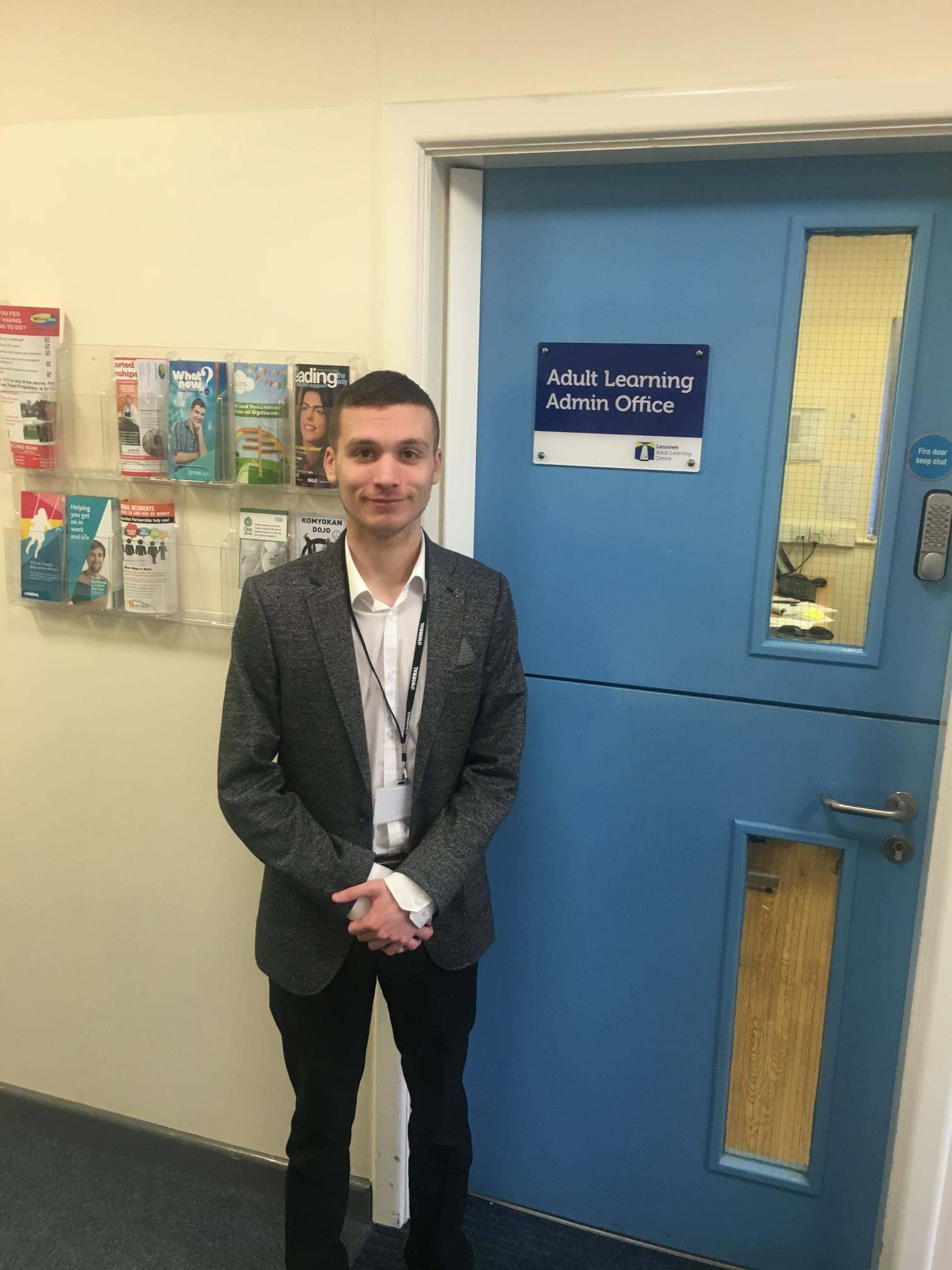 Man stood in front of a blue door in a suit