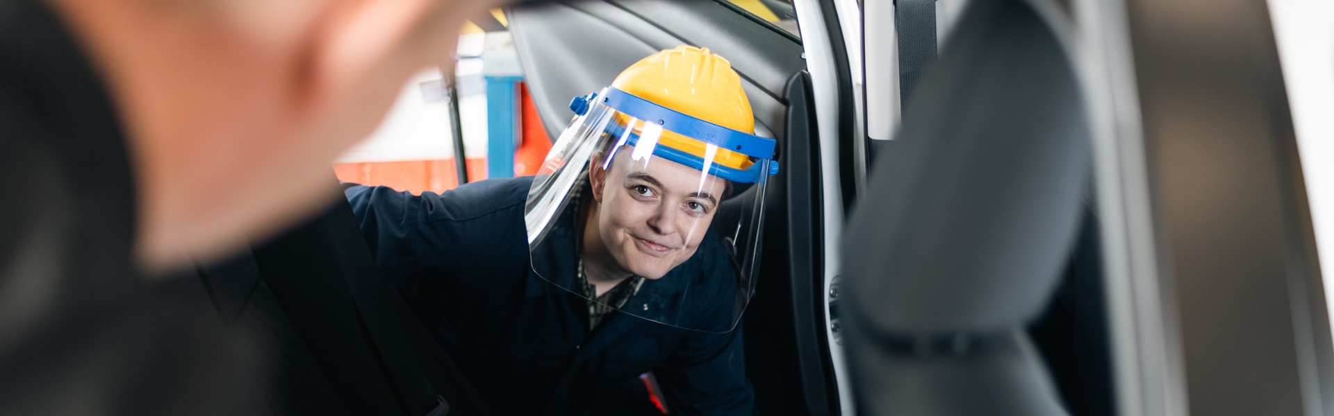 Automotive student working inside of a car wearing protective equipment