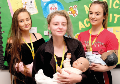 Three Female Childcare And Early Years Education Students Standing In lassroom