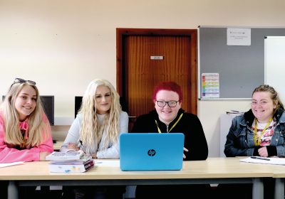 Four Full Time Social Studies Students Sat At Long Table In Classroom